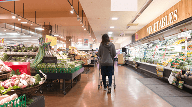 スーパー店内でカートを押す女性の画像