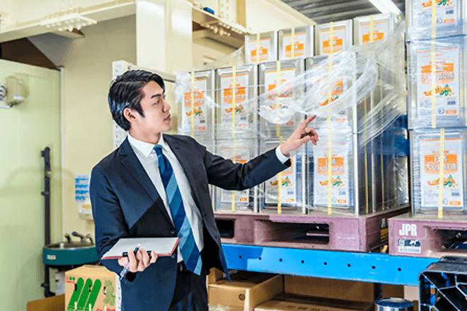 男性が倉庫で一斗缶を数えている画像