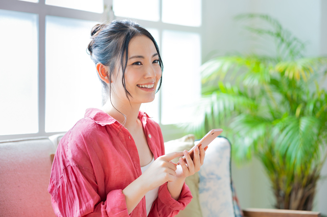 女性がスマートフォンを持っている画像