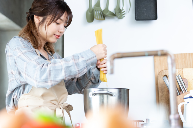 女性がパスタを湯でようとしているところの画像