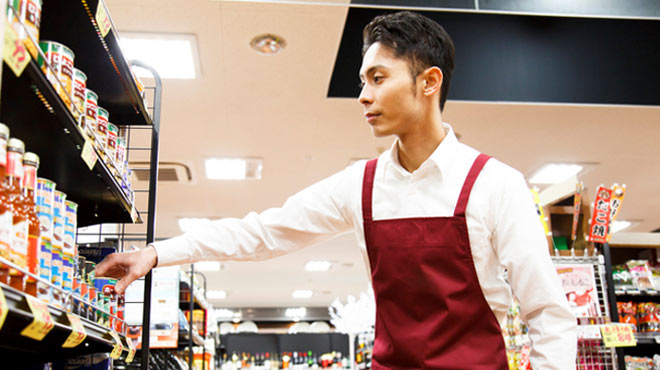 スーパーマーケットで男性店員が商品を整えているイメージ画像