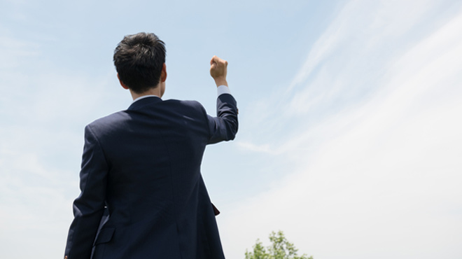男性が空に向かってこぶしをかがげているイメージ画像