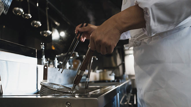 厨房内で調理している男性のイメージ画像