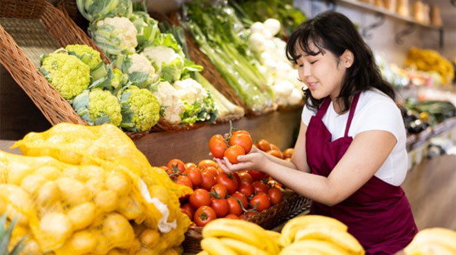 スーパーで野菜を手に取る従業員のイメージ画像