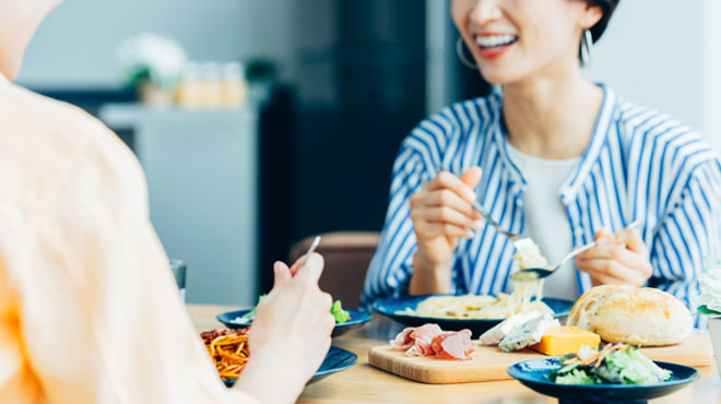 女性が食事しながら会話しているイメージ画像