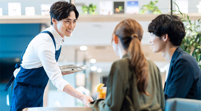 飲み物を置くウェイターと客のイメージ画像