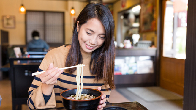 飲食店でうどんを食べている女性のイメージ画像