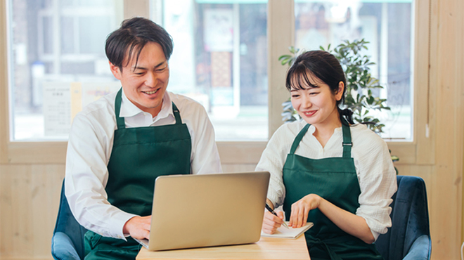 ノートパソコンの画面を見ながら笑顔のふたりのイメージ画像