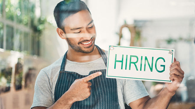 「HIRING(雇用)」の看板を持つ男性のイメージ画像