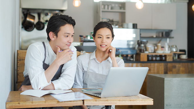 ノートパソコンを見ながら話し合うふたりのイメージ画像