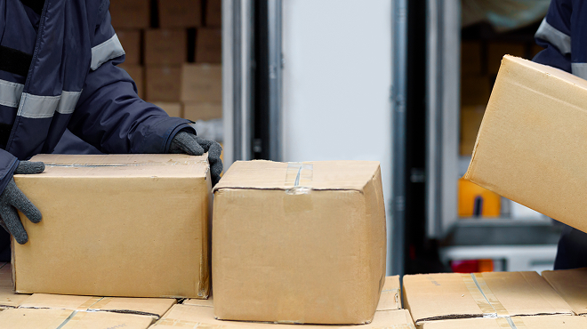 冷凍倉庫で段ボールを手作業で運ぶ様子。従来の在庫管理が人手と時間を多く必要とする課題を表現した写真