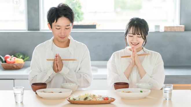 食卓で手を合わせている男女のイメージ画像