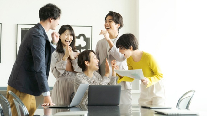 会議室で笑顔で会話する男女のイメージ画像