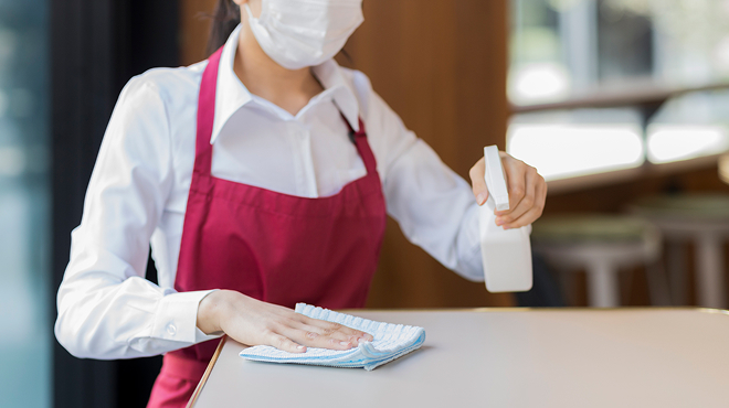 テーブルを消毒する店員のイメージ画像