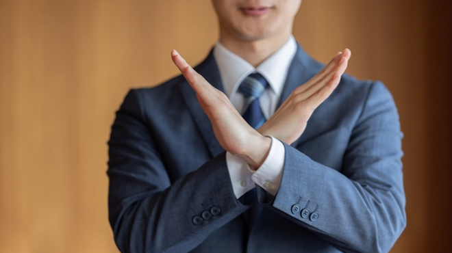 両手を交差させてNOのジェスチャーをしているイメージ画像