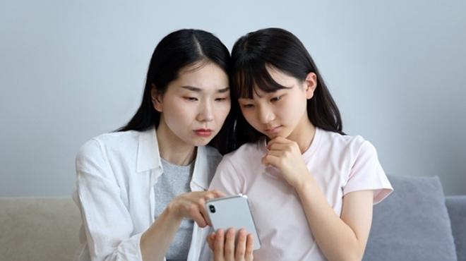 スマートフォンの画面を確認する大人とこどものイメージ画像