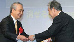 贈賞式で表彰状を受け取る鈴木社長（左：当時）