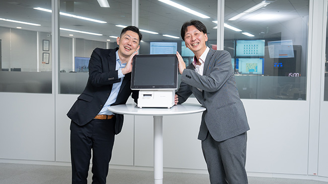 POS端末を前にポーズをとる関氏と三木氏