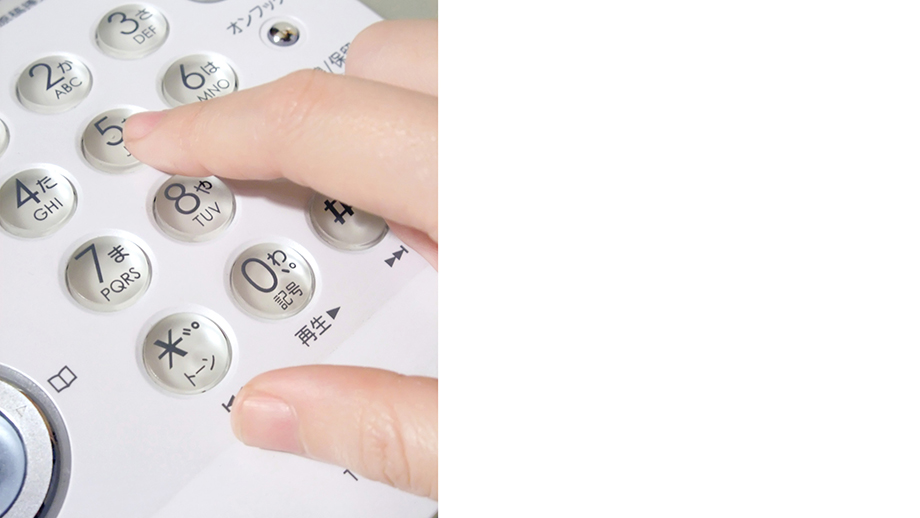 電話のボタンをプッシュしている手のイメージ画像