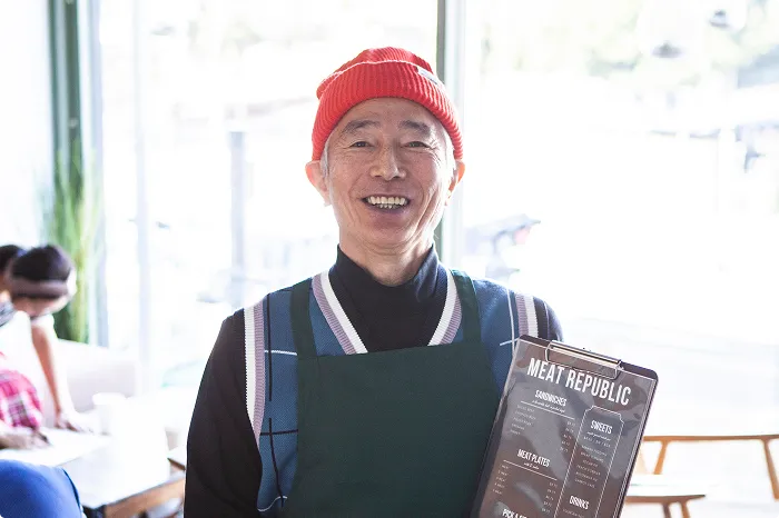 飲食店でメニューを持つ男性スタッフ