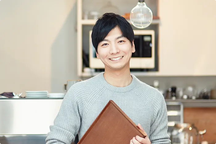 カフェでメニューを持つ男性スタッフ