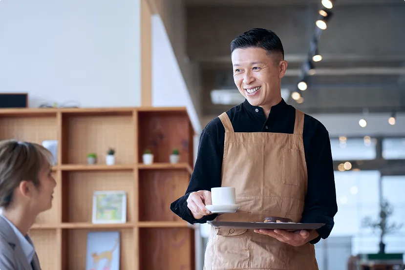 カフェでコーヒーを提供する男性スタッフ