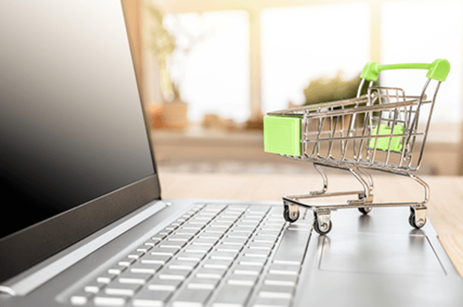 パソコンの上にミニチュアの買い物カートが載って画像