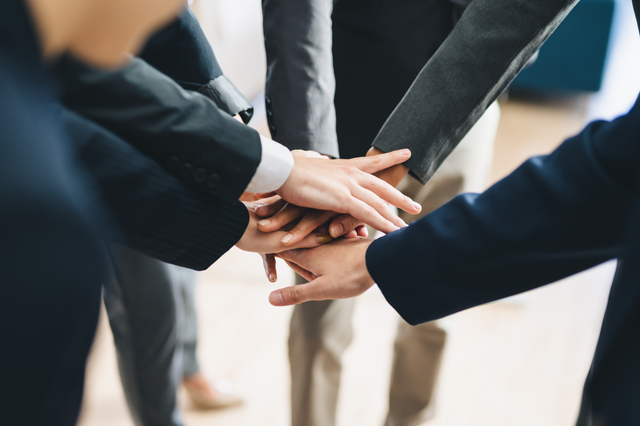スーツを着ている人たちが一致団結している様子を表している画像