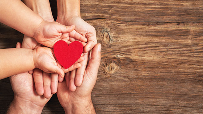 大人と子供の手のひらに赤いハートがあるイメージ画像