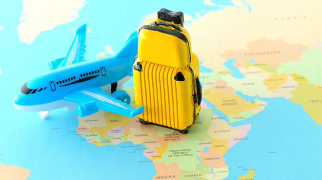 地図の上に置かれた飛行機とスーツケースの模型の画像