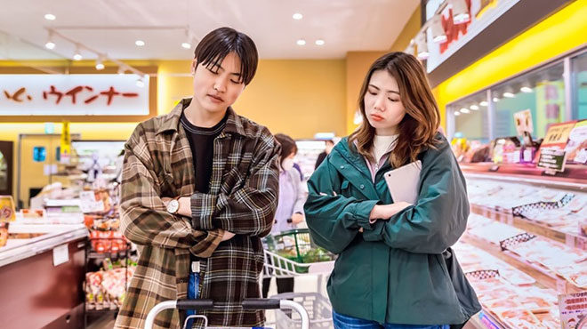 スーパーマーケットで腕を組んで考える人たちのイメージ画像