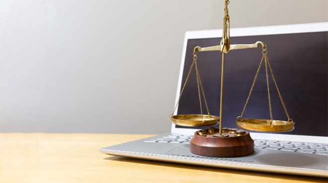 ノートパソコンの上に乗った天秤のイメージ画像