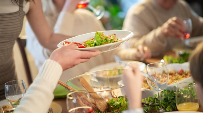 食卓でサラダやワインを楽しんでいるイメージ画像