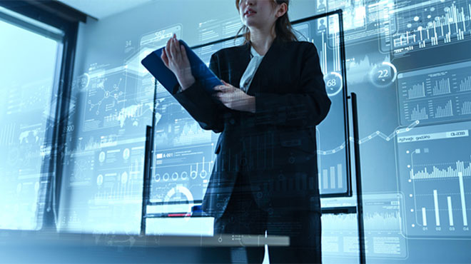 グラフなどを背景にして立つ人物のイメージ画像