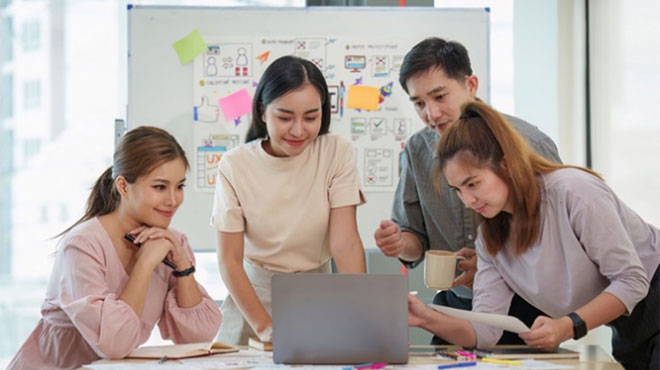 ノートパソコンを覗き込む人々のイメージ画像