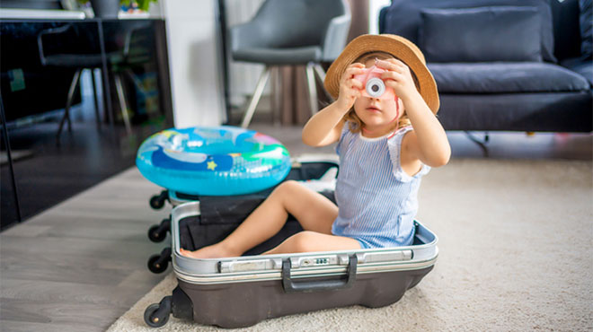 部屋で開いたスーツケースの中に座る子供のイメージ画像