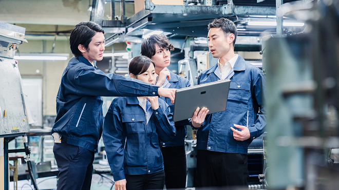 製造業の課題解決に向けてタブレットでデジタルツールを活用する現場作業員たち