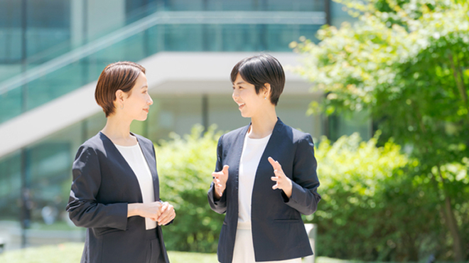 スーツを着た2人の女性が会話しているイメージ画像
