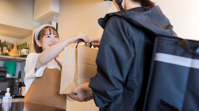 商品を配達員に渡す店員のイメージ画像