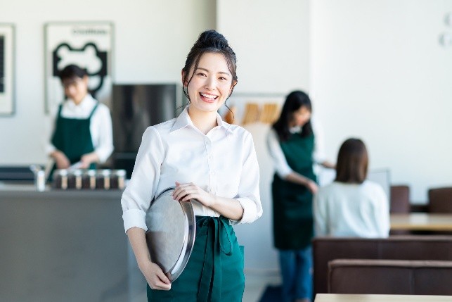 飲食店で笑顔で接客を行うスタッフのイメージ画像