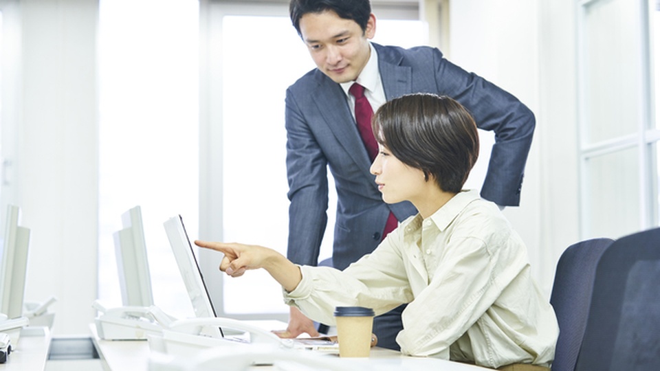 PC画面を見ながら話している男女の画像