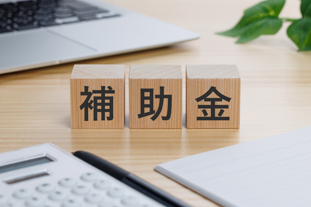 補助金と書かれたブロックが置かれたデスクのイメージ画像
