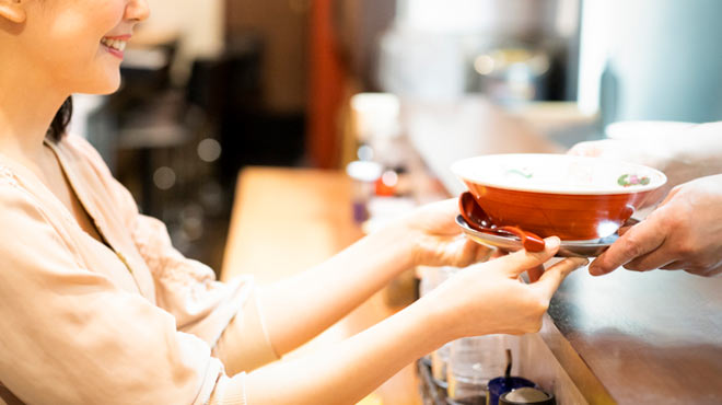 ラーメンを受け取る女性のイメージ画像