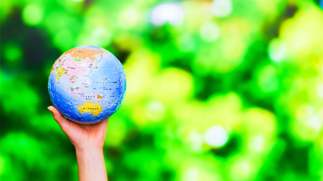 緑の背景と地球を持つ片手のイメージ画像