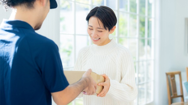 配送業者から小包を受け取る女性のイメージ画像