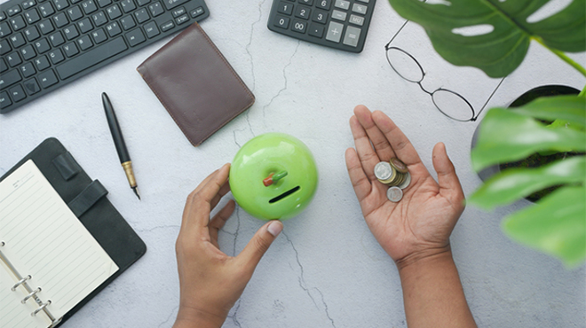 デスク上のキーボード、手帳、小銭を持つ手などのイメージ画像