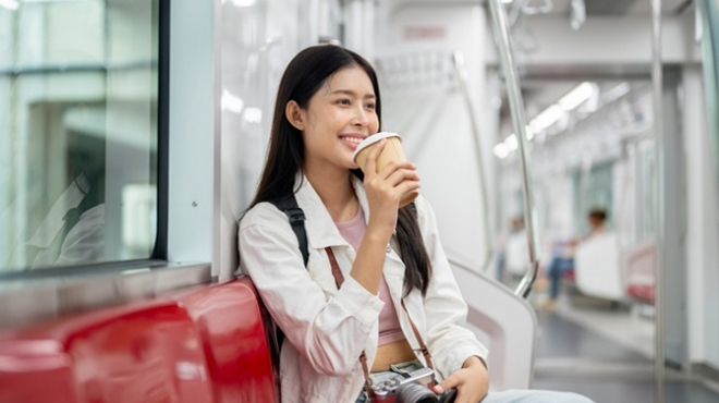 電車内でカップを持つ女性のイメージ画像
